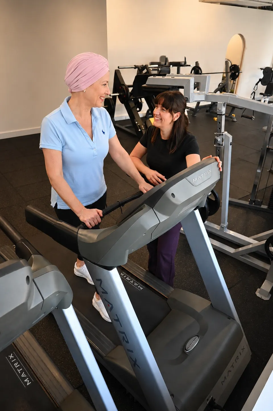 Physiotherapist guiding a patient through treadmill walking during cancer treatment